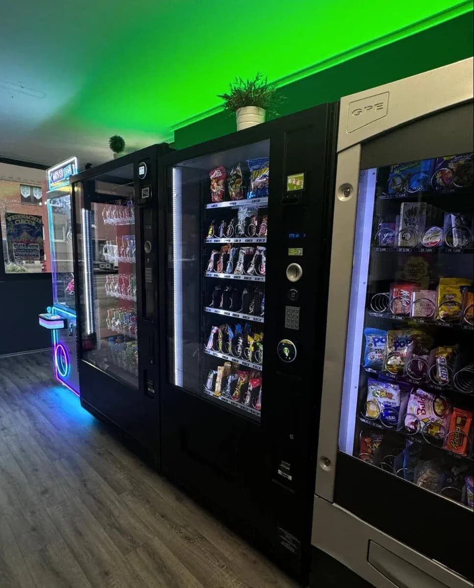 Getränke- und Snackautomaten in einem Selbstbedienungsraum mit grüner Lichtleiste